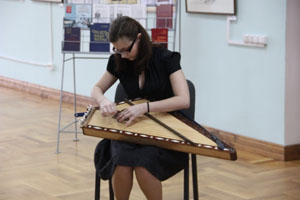 Студентка музыкального колледжа исполняет музыкальное произведение на гуслях